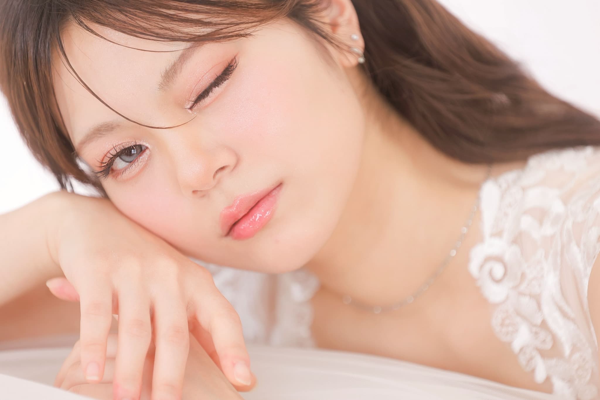 Close-up of a bride with soft rose makeup, loose hair and a white floral lace gown